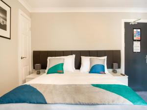 a bedroom with a large bed with blue and green pillows at OYO The Village Inn, Murton Seaham in Murton