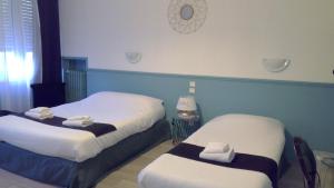 Dos camas en una habitación de hotel con toallas. en Hôtel Central en Carcasona