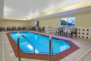 una piscina en una habitación de hotel con mesas y sillas en Candlewood Suites Rogers-Bentonville, an IHG Hotel, en Rogers