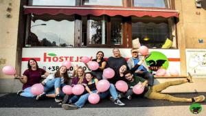 een groep mensen met roze ballonnen voor een bus bij Hostel 24 in Ljubljana