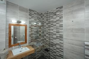 W łazience znajduje się umywalka i przeszklony prysznic. w obiekcie Hôtel Le Saint-Geniès w mieście Uzès
