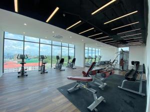 un gimnasio con equipo cardiovascular en una gran sala con ventanas en Regatta Suites Hotel at Kozi Square Kuching, en Kuching