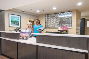 two people standing at a cash register in a waiting room at Candlewood Suites - Baton Rouge - College Drive, an IHG Hotel in Baton Rouge