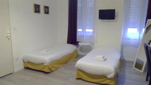 a room with two beds and a tv in it at Hôtel Central in Carcassonne