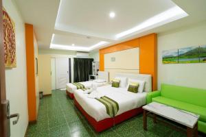 バンコクにあるラッキー グリーン ビューのベッド2台と緑のソファが備わるホテルルームです。