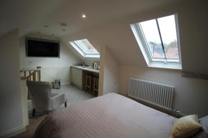 a bedroom with a bed and two windows and a desk at Granny's Attic at Cliff House Farm Holiday Cottages, in Whitby