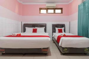 two beds in a room with pink walls at RedDoorz Plus @ Jalan Gatot Subroto Medan in Sunggal