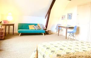 a bedroom with a blue couch and a table at Chambres chez l'habitant et table d'hôtes Crocq "le vieil hôtel" in Crocq