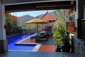eine Terrasse mit einem Sonnenschirm und einem Pool in der Unterkunft Villa Bukit Malas 4, 4 Bedroom Villa and Pool in Ambat