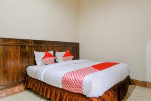 um quarto com uma cama grande e almofadas vermelhas e brancas em SUPER OYO 2643 Hotel Graha Prima em Tamperan