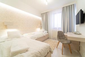 a white bedroom with two beds and a desk at Hotel Artin in Bardejov