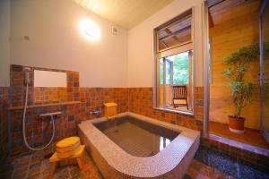 baño grande con bañera y ventana en Chuzenji Pension en Nikko