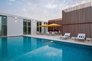 uma piscina com duas cadeiras e um guarda-sol em Staybridge Suites Al Khobar, an IHG Hotel em Al Khobar