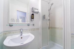 y baño blanco con lavabo y ducha. en Hotel Artin en Bardejov