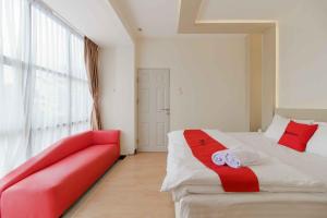 ein Schlafzimmer mit einem roten Sofa und einem großen Fenster in der Unterkunft RedDoorz Plus near Millenium ICT Centre Medan 2 in Pulauberayan