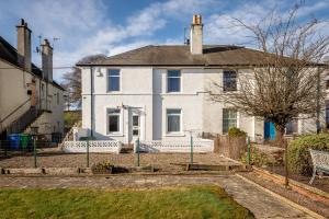 una casa blanca con una valla y un patio en The Eden Mill Residence, en St Andrews