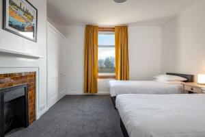 um quarto de hotel com duas camas e uma lareira em The Eden Mill Residence em St Andrews