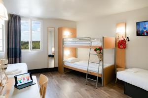 a room with two bunk beds and a desk with a laptop at B&B Hôtel près de Disneyland Paris in Magny-le-Hongre
