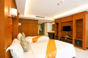 a bedroom with two beds and a flat screen tv at Tara Court Hotel in Pattaya South
