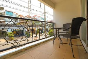 Un balcón con 2 sillas y una mesa frente a una ventana en Tara Court Hotel, en Pattaya South