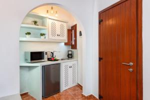 a small kitchen with a microwave and a door at Nectarios Villa - Studios & Suites Adults Only in Fira