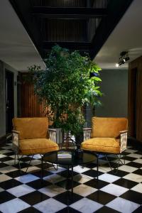 two chairs and a table in a room with a plant at Avenida 60 by NÔMA in Aveiro