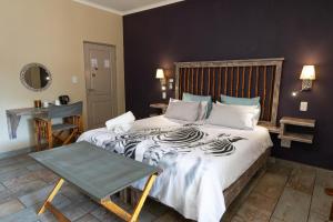 a bedroom with a bed and a lamp at The Belgium Inn in Hoedspruit