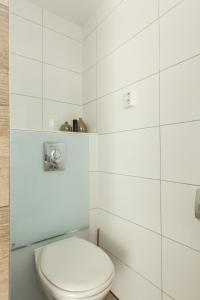 a bathroom with a toilet and a white tiled wall at SEA MORE in Zandvoort