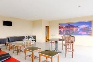 een woonkamer met tafels en stoelen en een schilderij aan de muur bij OYO Life 2966 Hotel Atriaz in Trenggalek