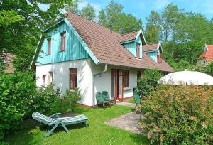 una casa verde e bianca con una panchina nel cortile di Ferienhaussiedlung Strandperlen Buchenhof 5a (Typ IV) a Wustrow