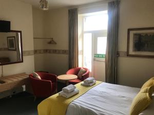 um quarto de hotel com uma cama e cadeiras e uma janela em The Sandpiper em Barmouth