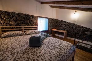 1 dormitorio con cama y pared de piedra en B&B La Casetta, en Aci Bonaccorsi