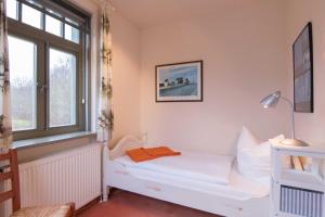 a small room with a white bed and a window at Ferienhaussiedlung Strandperlen Sanddornhof 7a (Typ VIII) in Wustrow