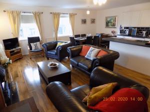 a living room with leather furniture and a kitchen at Oakdene Apartments in Windermere