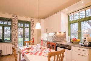 a kitchen with a table and chairs and a kitchen with windows at Ferienhaussiedlung Strandperlen Sanddornhof 3a (Typ VIII) in Wustrow