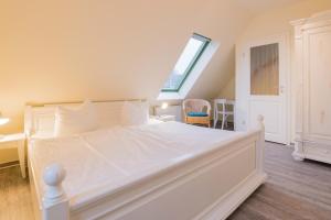 a bedroom with a large white bed with a window at Ferienhaussiedlung Strandperlen Sanddornhof 3a (Typ VIII) in Wustrow