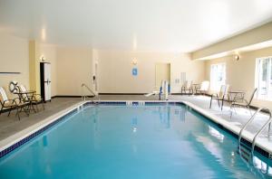 Candlewood Suites - Lancaster West, an IHG Hotel في لانكستر: مسبح في غرفة الفندق مع الكراسي والطاولات
