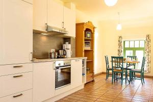 a kitchen with white cabinets and a table with chairs at Ferienhaussiedlung Strandperlen Küstenhof 1b (Typ V) in Wustrow