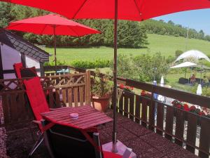 a red chair and a table with a red umbrella at Hennetaler Hof in Erflinghausen