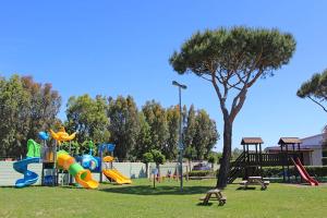 un parco con parco giochi con scivolo e struttura giochi di Villaggio Turistico La Cecinella a Marina di Cecina