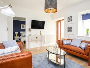 a living room with two couches and a table at 5 Porthdafarch South Cottages in Holyhead