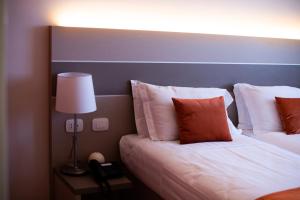 una camera d'albergo con due letti e una lampada di Hotel Glis a San Mauro Torinese