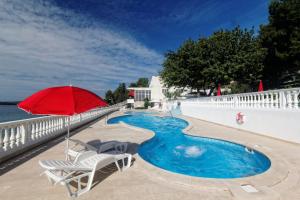 een rode parasol en stoelen naast een zwembad bij All Inclusive Hotel Val ex Jadran in Trogir