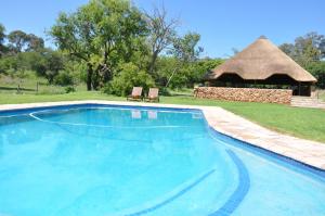 a swimming pool with a gazebo and two chairs at Intaba Thulile in Maanhaarrand