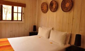 Schlafzimmer mit einem Bett mit weißer Bettwäsche und Kissen in der Unterkunft Intaba Thulile in Maanhaarrand