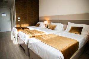 two beds in a hotel room with white and gold sheets at Hotel Glis in San Mauro Torinese