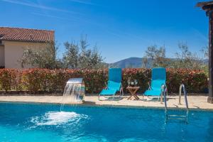 two blue chairs and a fountain in a swimming pool at Holiday house BRZAC in Brzac