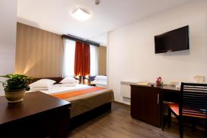 Habitación de hotel con cama, escritorio y TV. en Hotel Duke Armeneasca - Ex Tempo, en Bucarest