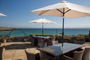 a table and chairs with an umbrella and the ocean at Port Charlotte Hotel in Port Charlotte