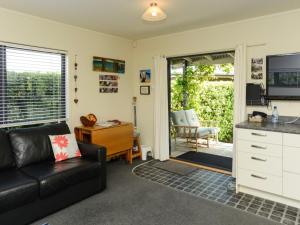 a living room with a black couch and a kitchen at Whamoori - Waimarama Beach Bach in Waimarama